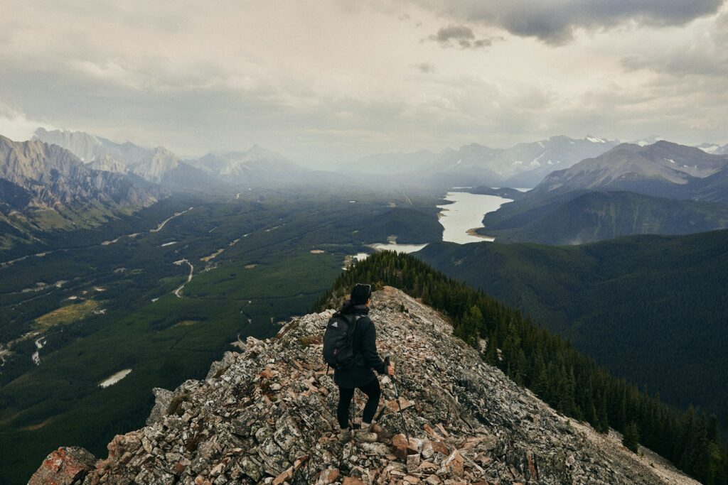 person in black jacket and black pants standing on rocky mountain during daytime